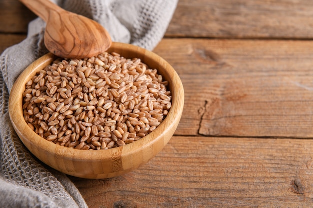 Vollkorn ungekocht roher Dinkel Farro in Schüssel auf dem hölzernen Hintergrund