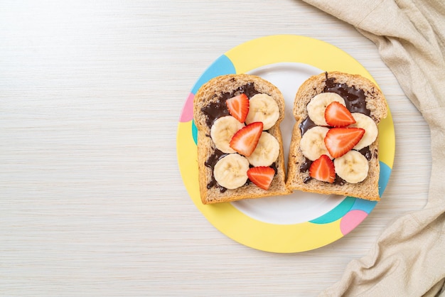 Vollkornbrot geröstet mit frischer Banane, Erdbeere und Schokolade zum Frühstück