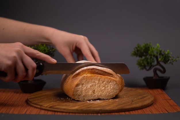 Vollkornbrot liegt auf einer Küchenholzplatte, die ein goldenes Schneidemesser hält. Frisches Brot.