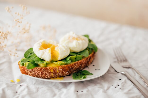 Vollkornbrot-Sandwich mit Avocado, Rucola und pochiertem Ei