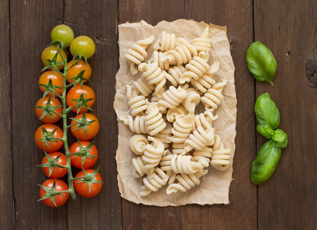 Vollkornnudeln, Tomaten und Basilikum auf Holz Draufsicht