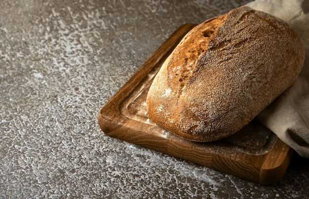 Vollkornroggenbrot auf einem Schneidebrett auf grauer Oberfläche