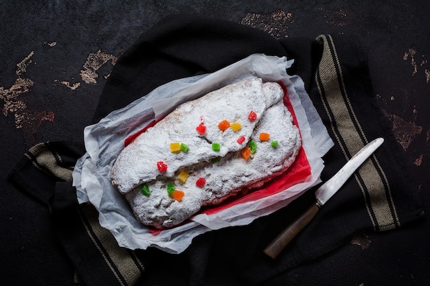 Vollkornstollen mit Rosinen und Puderzucker auf einer Leinenserviette mit Sieb