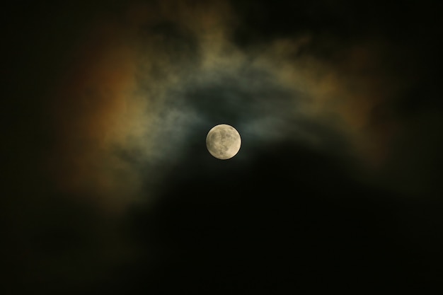 Vollmond auf dem dunklen Himmel mit dem Mondschein, der über die Wolken nachdenkt.