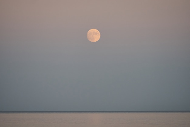 Vollmond steigt am Abend über dem Meer auf