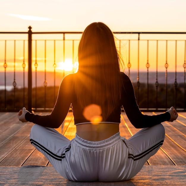 Foto vollschuss frau, die bei sonnenuntergang meditiert