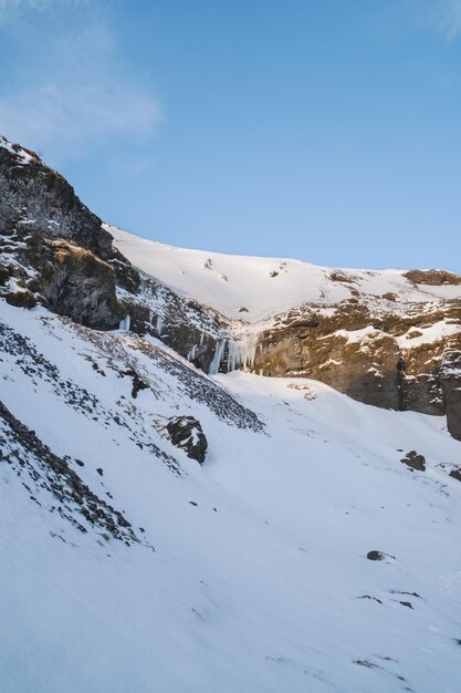 Vollständig schneebedeckter Berg in Richtung Kvernufoss-Wasserfall und eine Schlucht mit schneebedeckten Bereichen