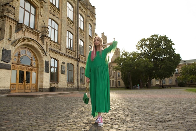 Vollständige Aufnahme einer atemberaubenden eleganten Frau, die ein langes grünes Kleid trägt und Sightseeing im ctiy macht