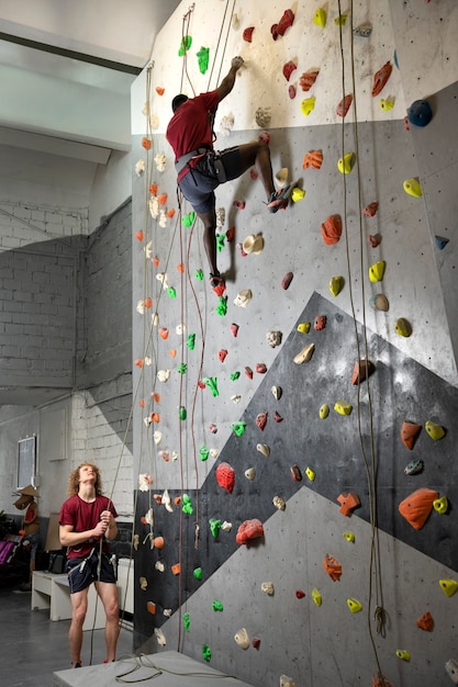 Foto vollständige aufnahme von freunden, die gemeinsam an der wand klettern