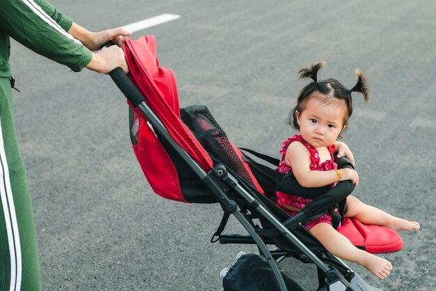 Vollständige Länge der jungen Mutter, die einen Kinderwagen im Park schiebt Seitenansicht der jungen Mutter beim Gehen im Park