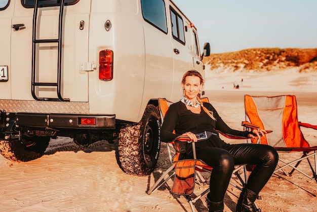 Vollständige Länge einer Frau, die an einem Lieferwagen am Strand sitzt