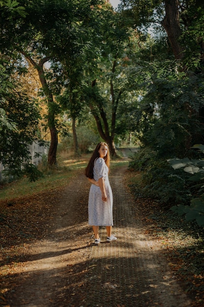 Vollständige Länge einer Frau, die auf einer Straße im Wald spazieren geht