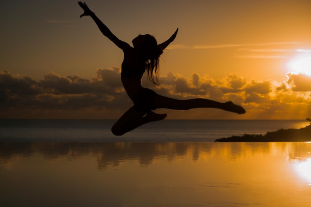 Vollständige Länge einer Frau, die im Infinity-Pool am Meer gegen den Himmel Ballett tanzt