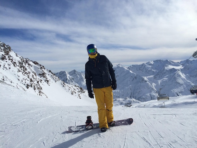 Vollständige Länge einer Person mit Ski auf einem Schneefeld gegen einen bewölkten Himmel