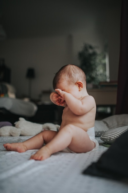 Vollständige Länge eines hemdlosen Babys, das zu Hause auf dem Bett sitzt