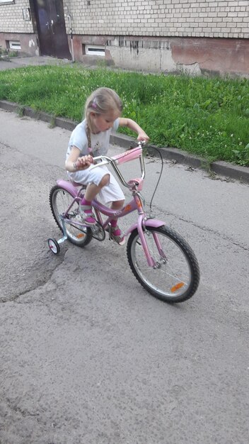 Foto vollständige länge eines mädchens, das fahrrad auf der straße fährt