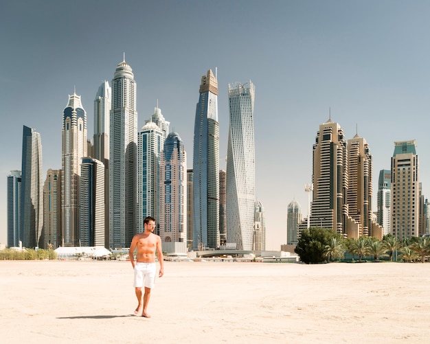 Vollständige Länge eines Mannes, der am Strand gegen Wolkenkratzer in der Stadt steht