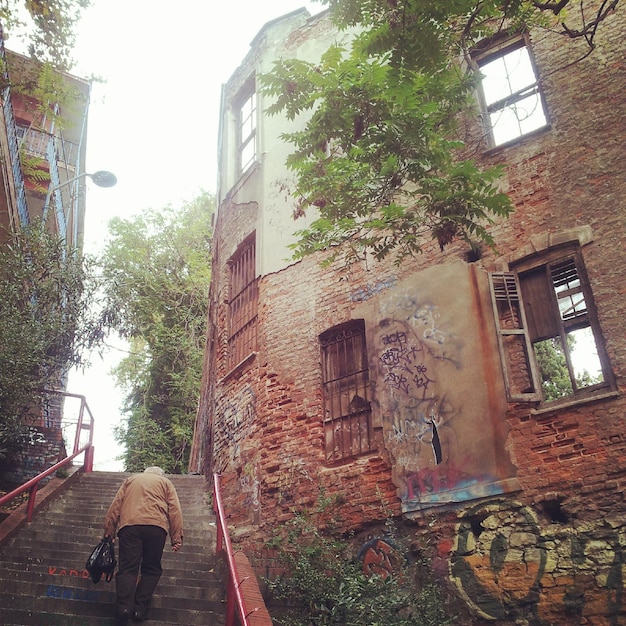 Foto vollständige rückwand eines mannes, der an den treppen von gebäuden gegen den himmel geht