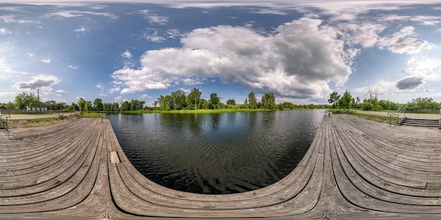 Vollständiges nahtloses sphärisches HDRI-Panorama 360-Grad-Winkelansicht auf Holzsteg von See oder Fluss mit schönen Wolken in equirectangulärer Projektion VR-Inhalt