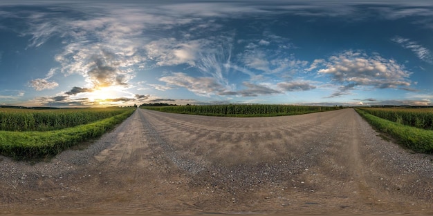Vollständiges nahtloses sphärisches Panorama 360-Grad-Winkelansicht auf Schotterstraße zwischen Feldern bei Sonnenuntergang am Sommerabend mit fantastischen Wolken in gleichrechteckiger Projektion Skybox VR-AR-Virtual-Reality-Inhalt