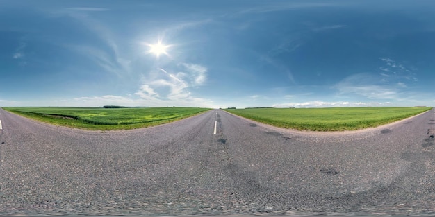 Vollständiges sphärisches nahtloses Panorama 360-Grad-Winkelansicht auf einer alten asphaltierten Straße ohne Verkehr zwischen Feldern mit klarem Himmel in equirectangulärer Projektion VR-AR-Inhalt