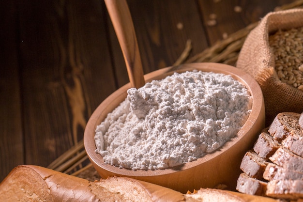 Vollweizenbrot, Mehlschlag und Hafer auf hölzerner Tabelle.