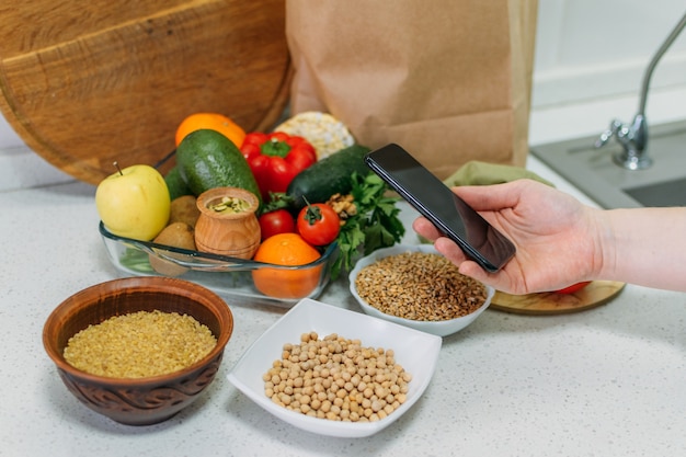 Vollwertkost pflanzliche Ernährung zur Steigerung der Gesundheit weibliches Handhandy mit pflanzlichen Menürezepten und