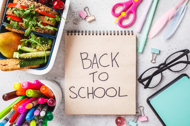 Foto volta ao conceito de escola com caixa de almoço com sanduíche, frutas, lanches, notebook, lápis e itens de escola