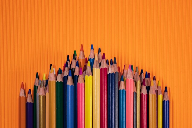 Foto volta ao conceito de escola. lápis de cor em fundo laranja.