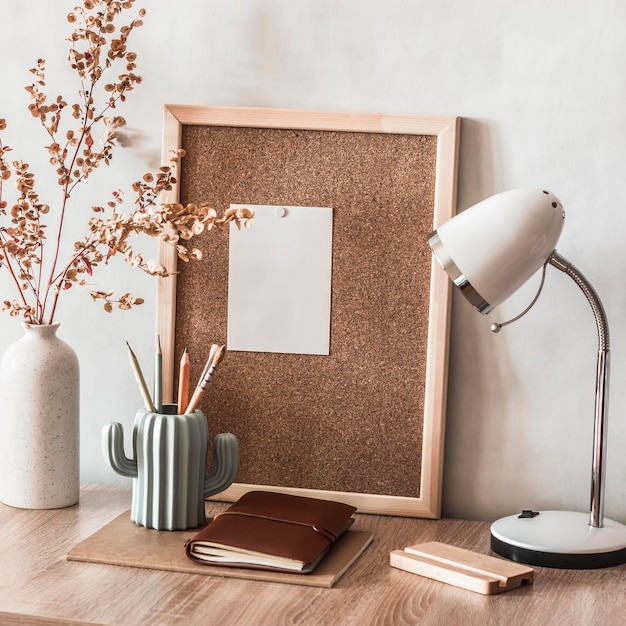 Volta às aulas A casa de trabalho do aluno Uma mesa com material didático um quadro de cortiça para anotações um candeeiro de mesa lápis e um vaso decorativo com flores secas