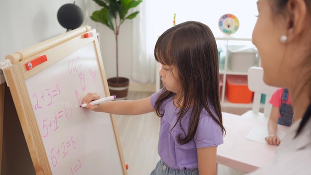 Volta às aulas e curso de verão. professor de jardim de infância com crianças desenhando e colorindo.