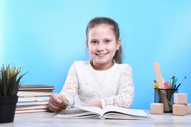 Voltar para a escola. Criança bonita e industriosa feliz está sentado em uma mesa dentro de casa. Garoto está aprendendo em sala de aula. Quarentena. Criança está aprendendo em casa.