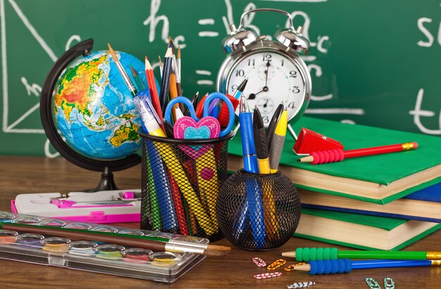 Voltar para a escola - quadro-negro com caixa de lápis e equipamento escolar na mesa