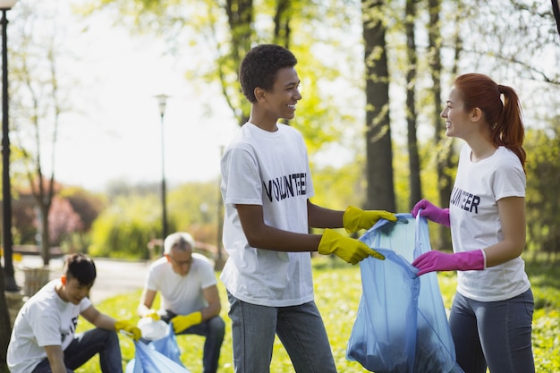 Voluntariado ambiental. Dois voluntários positivos segurando um saco de lixo e olhando um para o outro