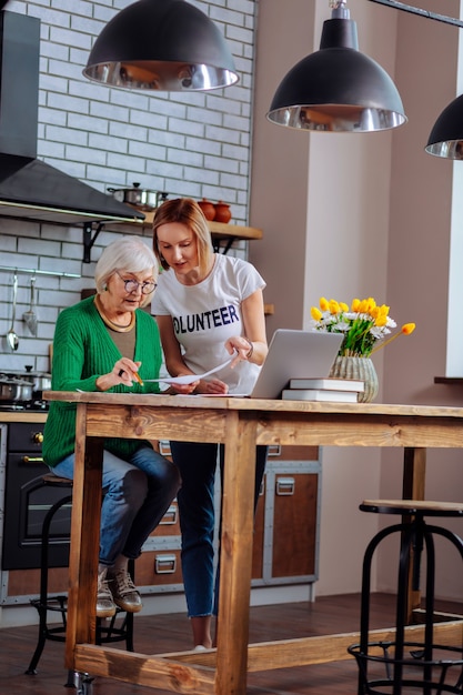 Voluntario adulto joven discutiendo con una anciana en la cocina