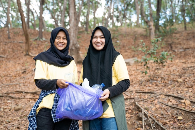 Voluntário asiático do hijab da mulher que guarda o saco de lixo