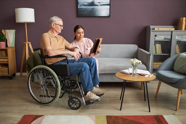 Voluntario ayudando a un anciano a usar tablet pc