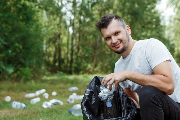 Un voluntario con una bolsa de basura recoge plástico.