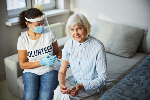 Voluntario dando una inyección en el brazo de un pensionista