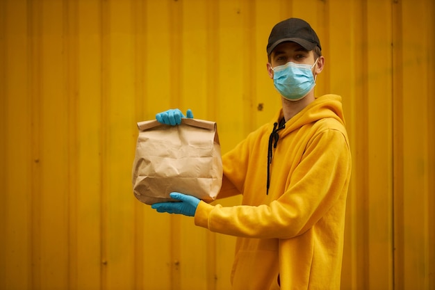 Voluntário de correio em um fundo amarelo com um pacote Voluntário de correio com um pacote fechado