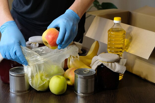 Voluntário em luvas de proteção embala produtos na caixa Entrega de comida durante