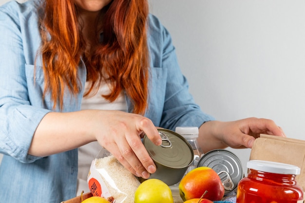 Voluntario empacando diferentes productos en caja de donación para personas aisladas.