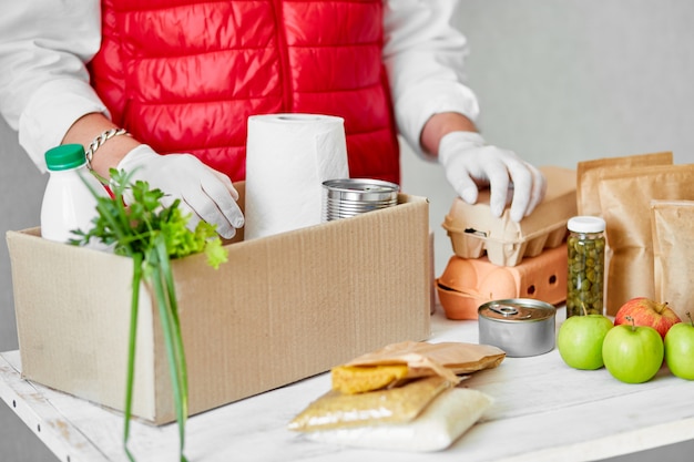 Voluntario con guantes quirúrgicos poniendo comida en la caja de donación