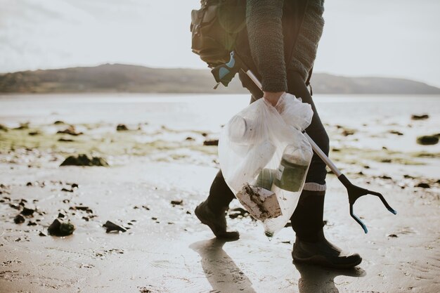 Voluntario de limpieza de playa que lleva una bolsa de basura para la campaña medioambiental