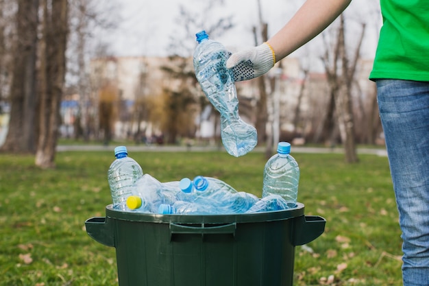 Foto voluntario poniendo botellas de plástico en basura