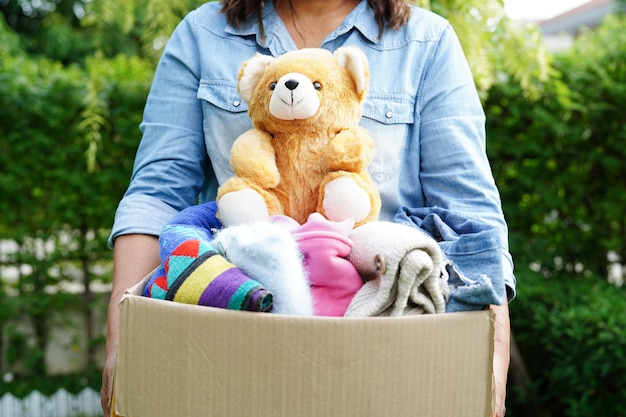 Foto voluntario recoge tela y muñeca en caja de cartón para donar