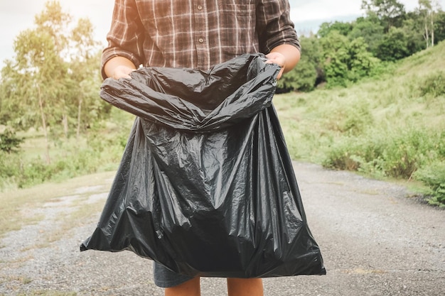 El voluntario recogiendo una botella de plástico en una bolsa de basura para limpiar la contaminación ambiental