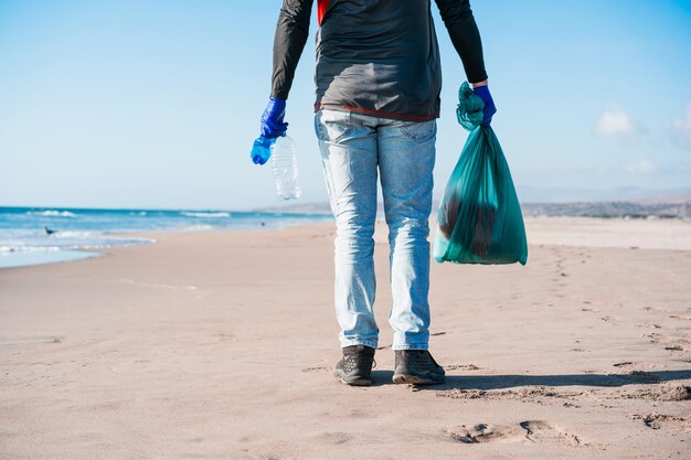 Voluntário recolhe resíduos plásticos na vista traseira da praia