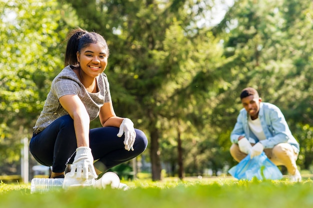 Voluntarios afroamericanos recogiendo basura plástica en un día soleado en el parque de verano