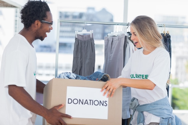 Voluntarios alegres mirando una caja de donación